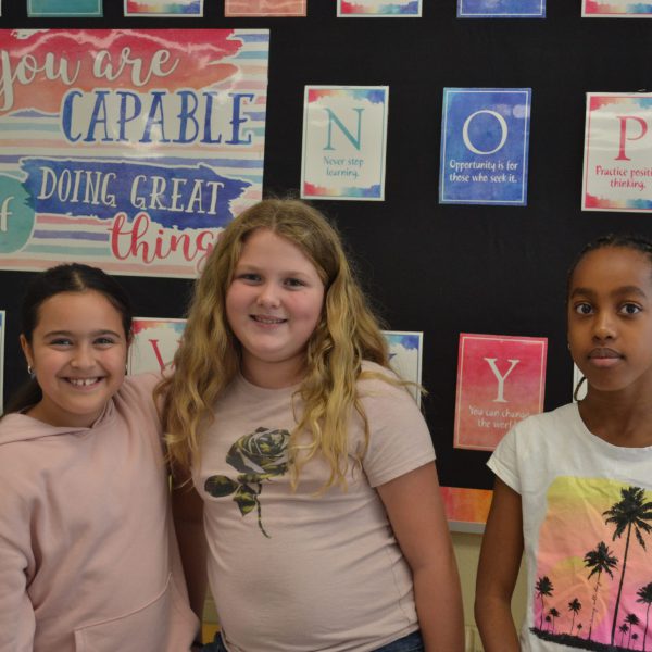 three female students in front of bulletin board