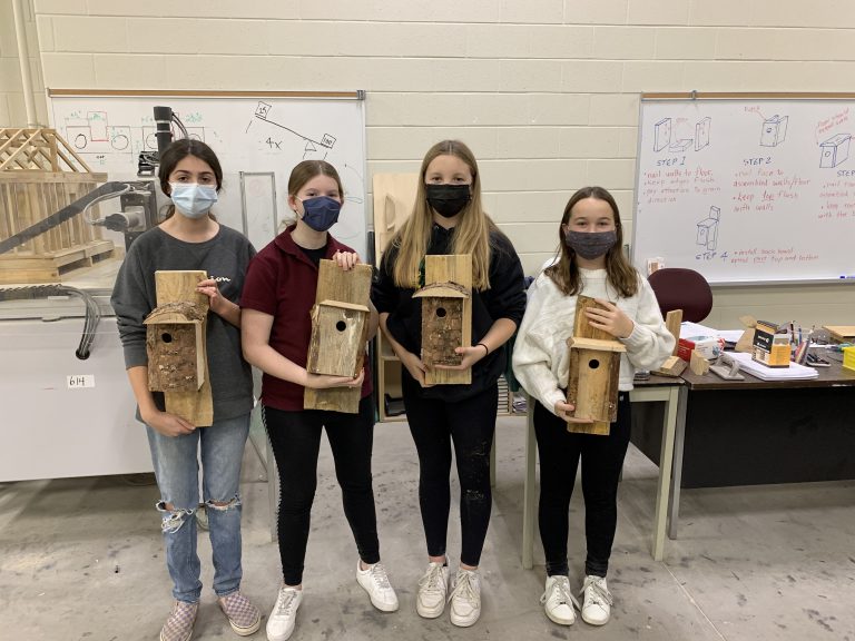 four students with birdhouses
