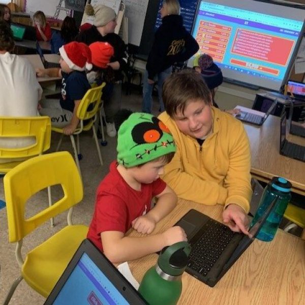 Older student helps younger student on computer
