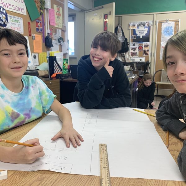 Three males students at a table doing a project