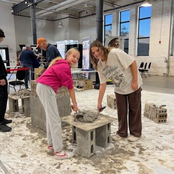 Two female students mixing cement at a trades career fair