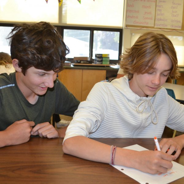 student watches fellow student writing