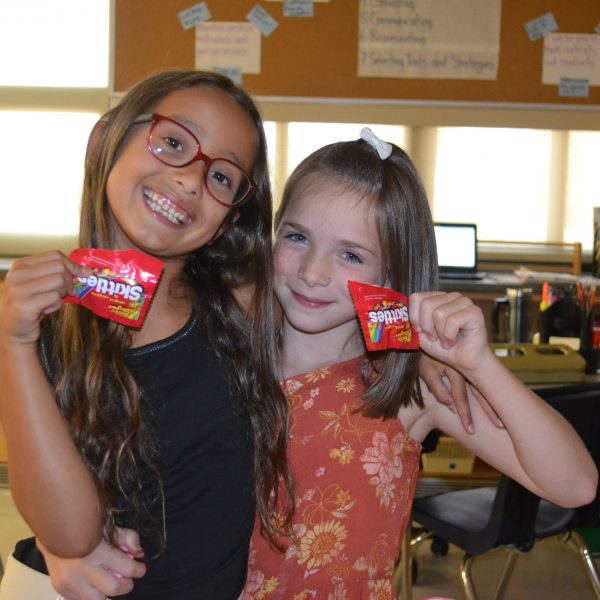two female students hold up skittles packages