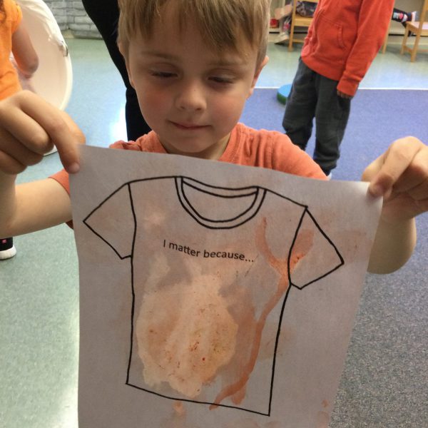 student with orange shirt drawing