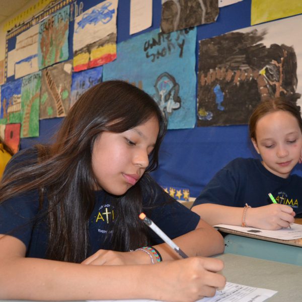 Two female students writing at their desks