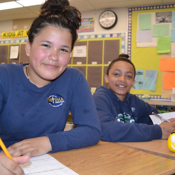 Two students at their desks pose for the camera