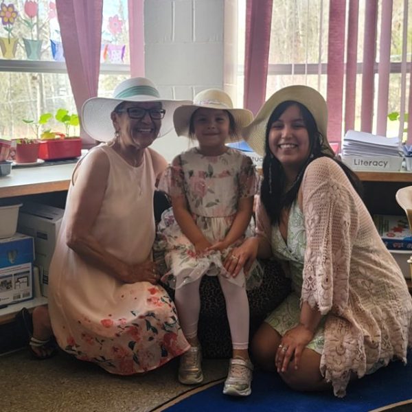 A students stands between two adult women wearing sun hats