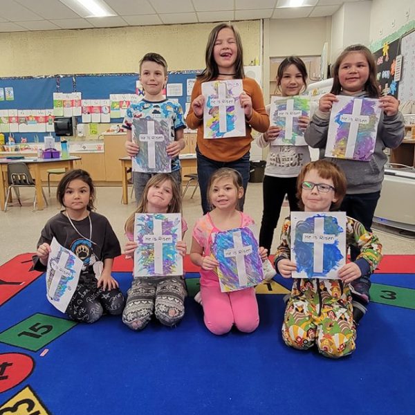 Students hold up artwork showing crosses