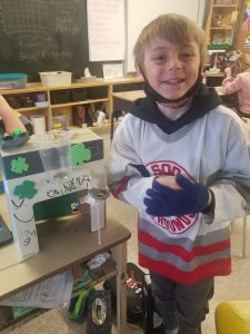 student stands beside leprechaun trap