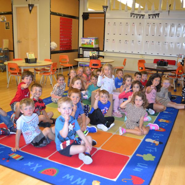 students hold up one finger to signifying the first day of school