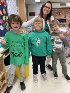 Three boys and staff member dressed in green