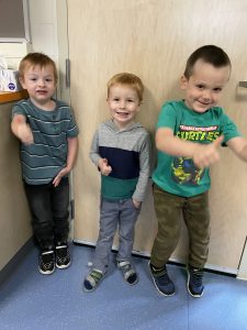Three boys dressed in green giving the thumbs up