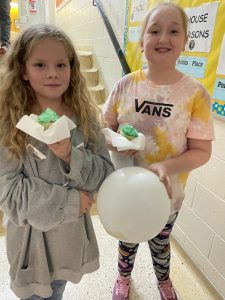 Two girls with green icing cupcakes