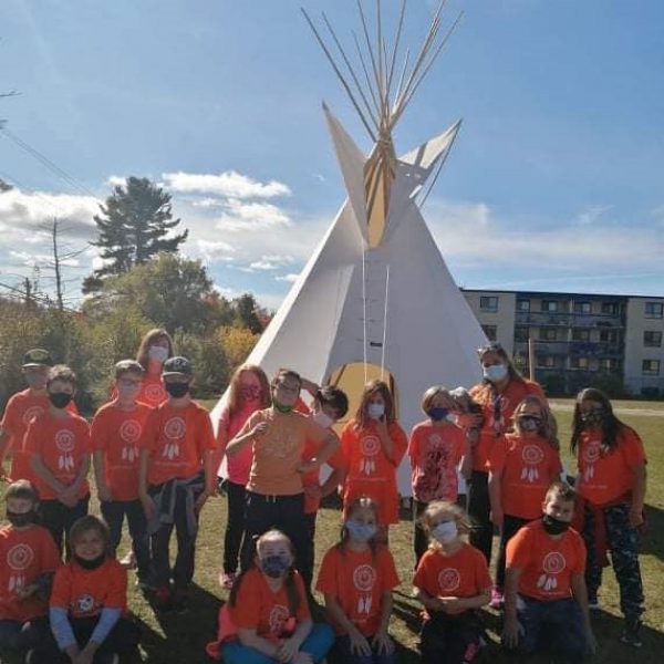 students in front of a tipi