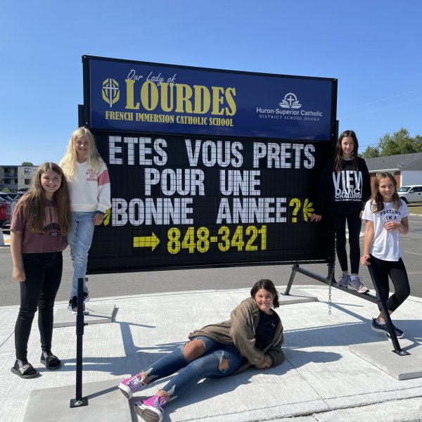 students pose on french side of portable sign