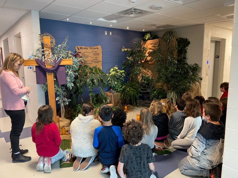 students pray in front of Holy Week display