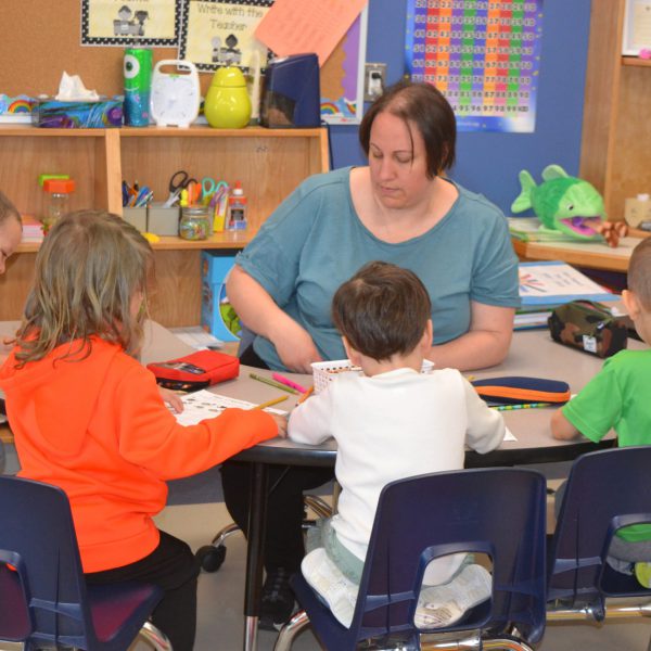 Kindergarten students at desk with educator