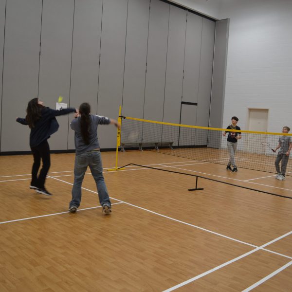 Students playing badminton in gymnasium