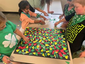 students at desk putting together artwork