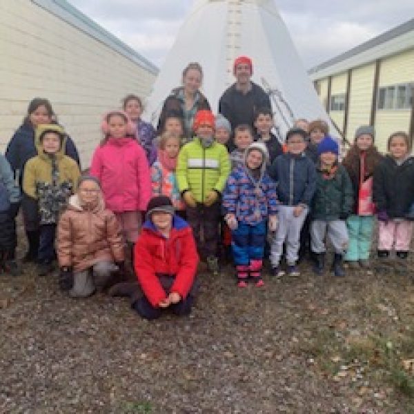 First class of students who used teepee pose in front of it