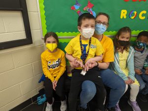 students and staff member in yellow and blue