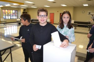 Male student puts ballot in box