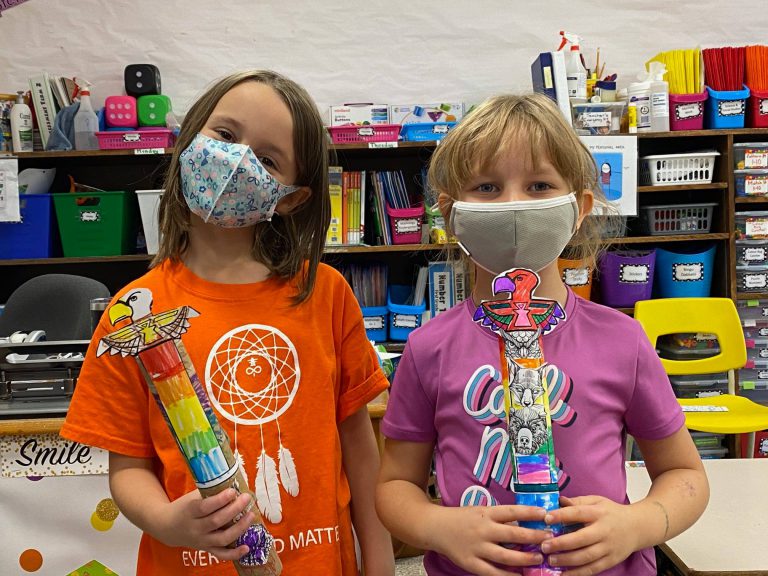 two students with paper toem poles