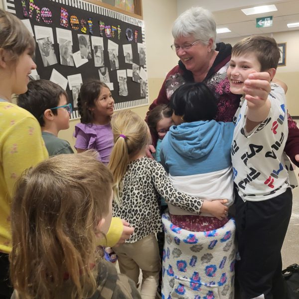 Students hug Mrs. Thibeault on Administrative Assistants Day