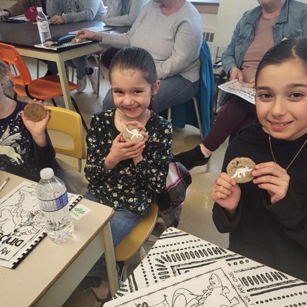 Students show their dinosaur cookies after reading by local author
