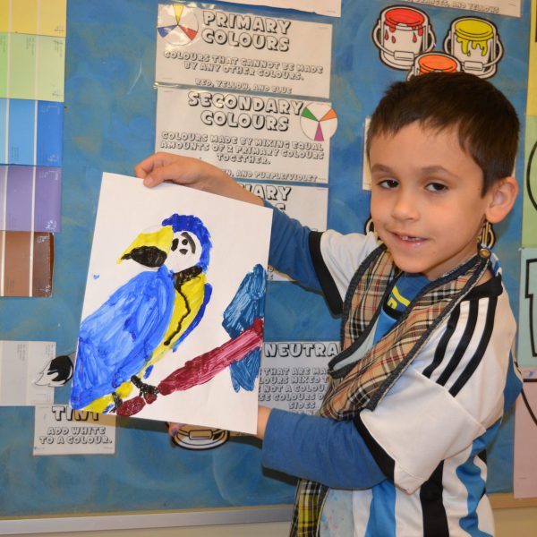 Male student shows his drawing of a parrot