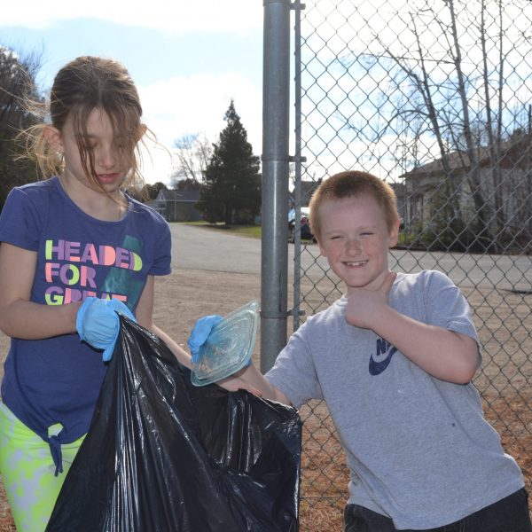 Two students collecting refuse in school yard