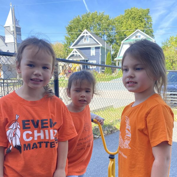 Three primary students in outside play area wearing orange shirts