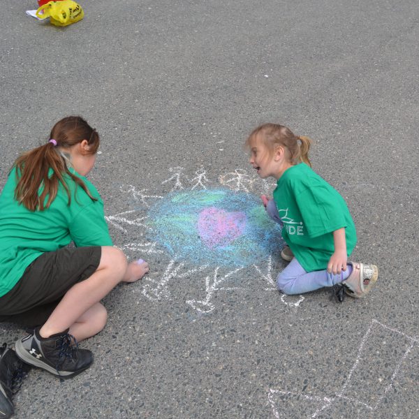 Two students doing a chalk drawing on pavement