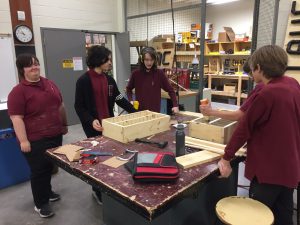 Students work on gluing cell phone holders in shop class