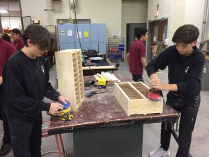 Two students sanding cell phone holders