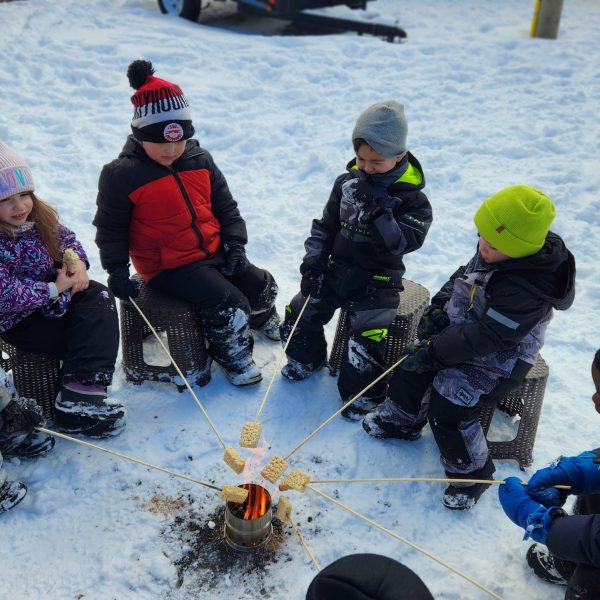 Students with sticks at a campfire