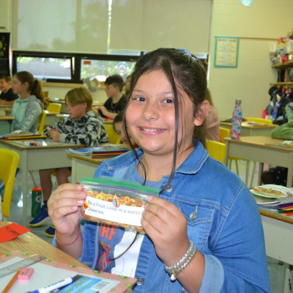 student holding a bag that says be a Fruit Loop in a world of Cheerios