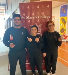 Three newcomer students pose in front of school banner at St. Mary's College