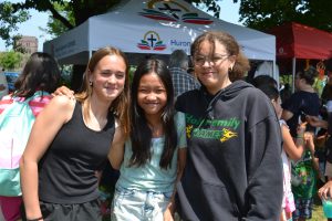 Three studnts in front of the school board booth at the Indigenous Day Pow Wow